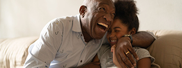 A retiree smiling and hugging his granddaughter happy knowing she will be taken care of for generations to come through legacy planning and a personal trust.