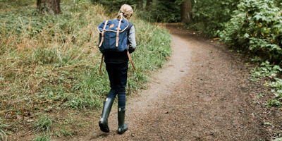 Woman hiking on wooded path, enjoying life with optimal retirement options from Principal.